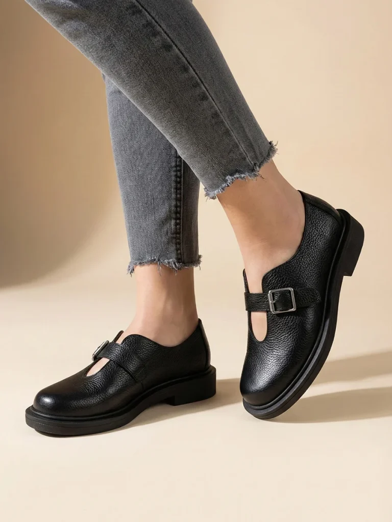 Czarne skórzane półbuty damskie Vesta w stylu barefoot z szerokim noskiem i srebrną klamrą na grubszej podeszwie.